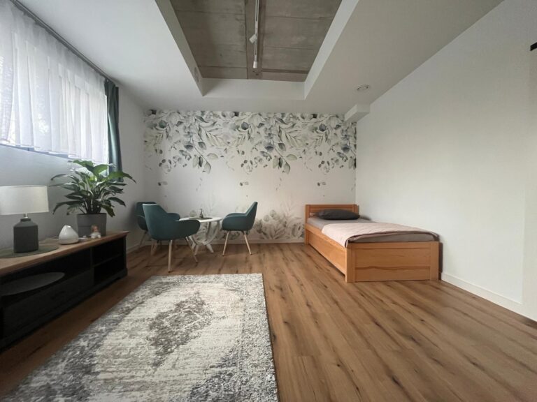 Przytulny pokój seniora z łóżkiem i miejscem do odpoczynku – Seniorlandia dom opieki komfortowe zakwaterowanie