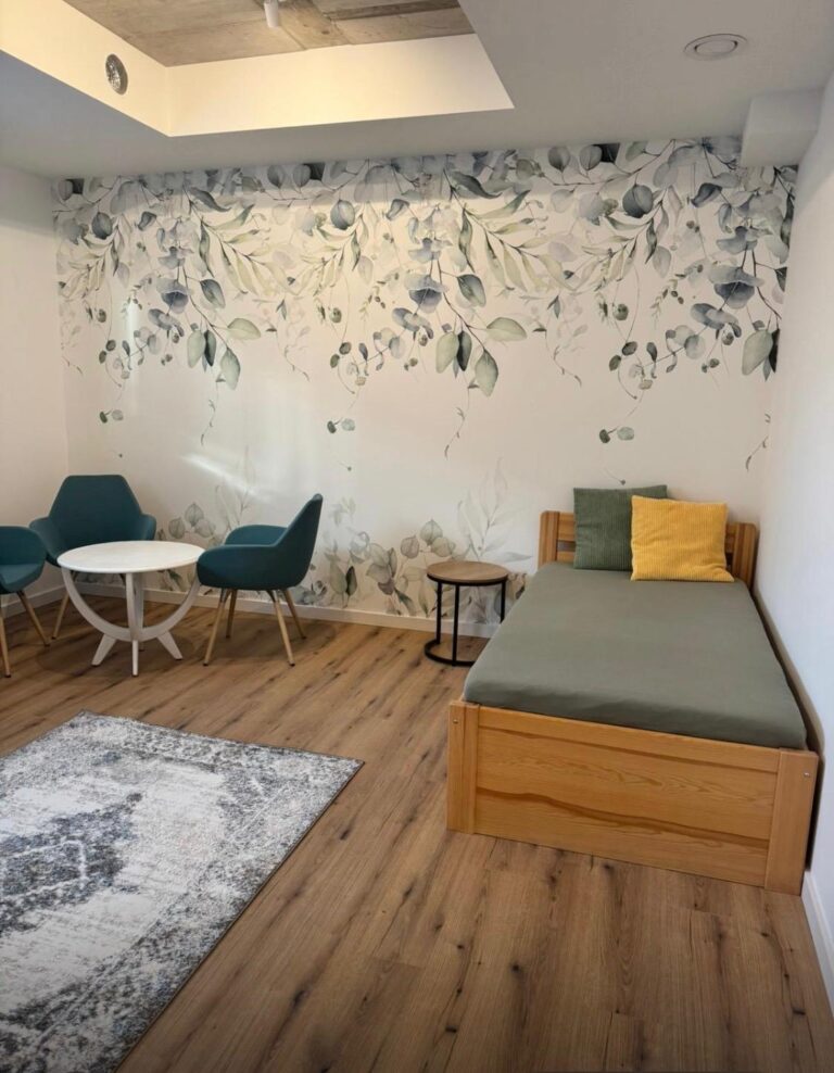 Pokój dzienny z tapetą kwiatową i miejscem do rozmów – Seniorlandia dom opieki spokojna strefa odpoczynku